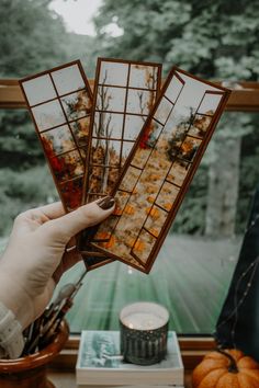 a person holding up three pictures in front of a window with autumn decorations on it