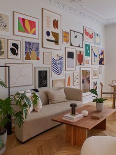 a living room filled with furniture and lots of pictures on the wall next to a coffee table