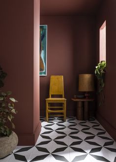 a yellow chair sitting in the middle of a room next to a potted plant