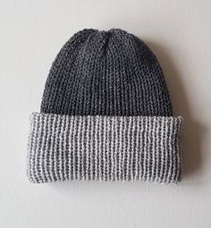 a gray and white striped beanie with a black patch on the side, hanging from a wall