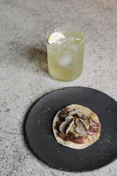 a black plate topped with food next to a drink