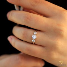 a woman's hand with three diamond rings on her finger and the other hand holding an engagement ring