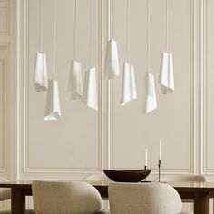 a dining room table with chairs and lamps hanging from the ceiling