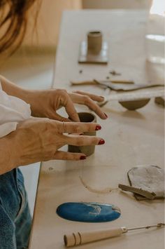 a woman sitting at a table working on pottery