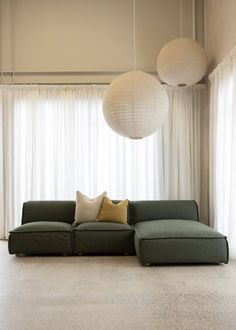 a green couch sitting in front of two white lamps