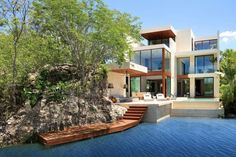 a large house sitting on top of a lush green hillside next to a body of water