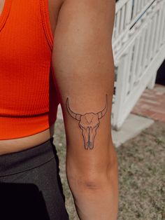 a woman's arm with a tattoo of a bull skull on the left side