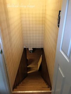 an open door leading to a hallway with wooden steps and tiled walls in the background