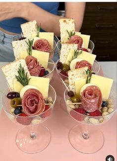 two wine glasses filled with different types of cheese and meats on top of each other