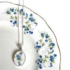 If you are seeking a romantic 9th (pottery), 18th (porcelain) or 20th anniversary (china) gift for your wife that she will always cherish, commemorate your love and this anniversary with this forget me not flower china necklace from eclectiQuas. This unique blue flower necklace features a dainty blue floral broken china pendant in an oval sterling silver setting and chain, and a repurposed china piece from a vintage forget me not china plate. In addition to being a beautiful fine bone china gift, this broken china jewelry piece highlights forget me not flowers that symbolize love, fidelity, and remembrance, promising that you will never forget the recipient, an occasion, a person in your thoughts. They also symbolize a connection that endures all challenges and measure of time. She will ch Repurposed China, Red Chinoiserie, 20th Anniversary Gifts, Piece Highlights, Elegant Gift Wrapping, Jewelry Sets Handmade, Porcelain Necklace, Forget Me Not Flower, Broken China Jewelry