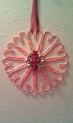 an ornament hanging on the wall with pink string and beads in it's center