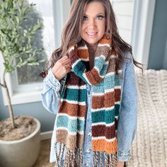 a woman wearing a multicolored crocheted scarf with fringes on it