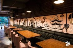 an empty restaurant with wooden tables and chairs in front of a mural on the wall