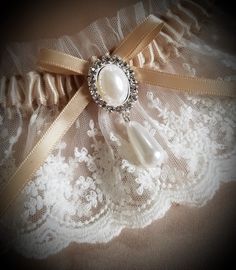 This vintage look garter is lovely in light ivory net lace over a champagne satin band. Decorated with a faux pearl and crystal finding. This garter is also available in plus size, just convo me with questions or your own design ideas! A blue satin rolled rose can be added to the inside of the band for your 'something blue'. Packaged in a view-top box tied with an elastic metallic bow, perfect for gift-giving or for safe-keeping after the wedding. Elegant Lace Bridal Accessories For Bridal Shower, Fitted Cream Lace For Wedding Night, Fitted Delicate Cream Lace, Delicate Fitted Cream Lace, Cream Fitted Delicate Lace, Adjustable Lace Bridal Accessories For Ceremony, Cream Lace Bridal Accessories For Party, Elegant Lace Bridal Accessories For Ceremony, Elegant Fitted Lace Bridal Accessories