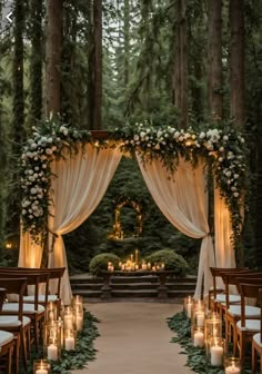 an outdoor ceremony with candles and greenery on the aisle, surrounded by tall trees