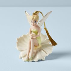 a figurine sitting on top of a flower with a tassel hanging from it's side