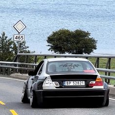 a car driving down the road with graffiti on it's hood and back window