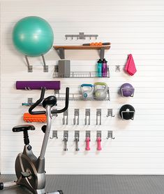 an exercise bike in front of a wall with gym equipment on it and a ball hanging from the ceiling