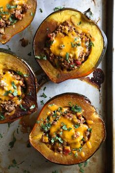 four stuffed acorns with meat and cheese in them on a baking sheet, ready to be cooked