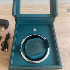 an open box with a ring in it on a table next to a charger