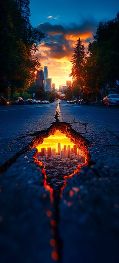 a reflection of the sun in a puddle on the ground with trees and buildings in the background