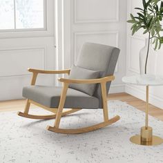 a rocking chair in a living room next to a table with a potted plant