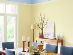 a dining room with yellow walls and blue chairs