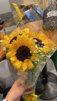 a person holding a bouquet of sunflowers in front of a table with other flowers