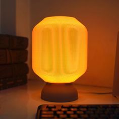 a yellow lamp sitting on top of a desk next to a keyboard