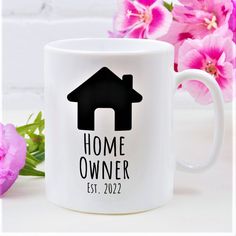 a white coffee mug with the words home owner next to it and some pink flowers