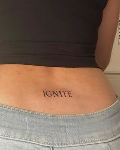 a woman's stomach with the word ignte tattooed on it