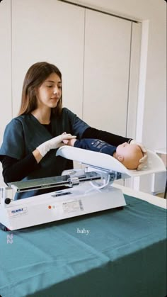 a woman in black shirt holding a baby on top of a hospital bed next to an iv machine