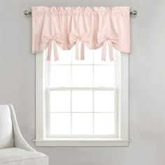 a white chair sitting in front of a window with pink drapes on the windowsill