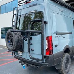 the back end of a blue van parked in a parking lot with its door open