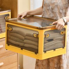 a woman is holding a yellow dog crate