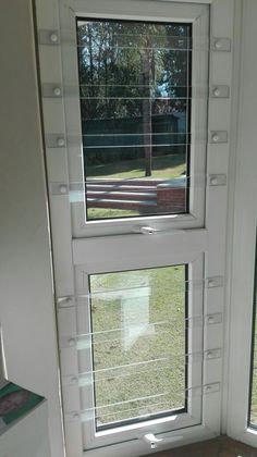 two windows with blinds on each side of the door and one window has a reflection of a tree in it