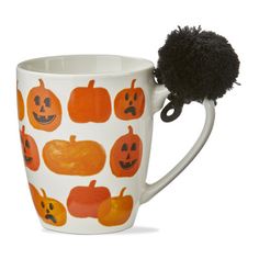 a coffee cup with pumpkins on it and a black pom - pom