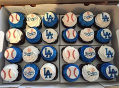 cupcakes with blue and white frosting are in a box on the table