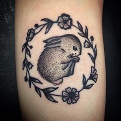 a tattoo with an image of a rabbit in a circle surrounded by leaves and flowers