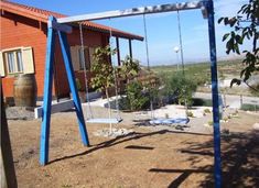 an empty swing set in front of a red building with a blue tint on it