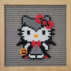 an image of a cross stitch hello kitty with pumpkins on her head in a frame