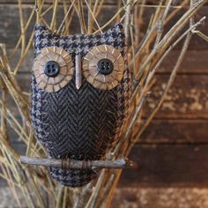 an owl figurine sitting on top of a branch in front of a wooden wall