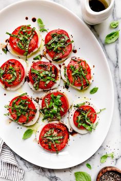 a white plate topped with sliced tomatoes and basil