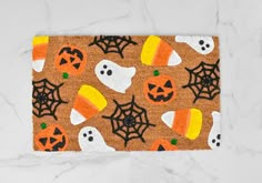 a door mat with halloween decorations and pumpkins on it in front of a marble wall