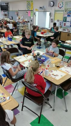 a group of children sitting at desks in a classroom with paper decorations on them