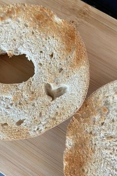 two bagels sitting on top of a wooden cutting board