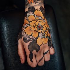 a tattooed hand with yellow flowers on it