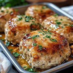 meatballs covered in gravy and parsley on a baking pan with sauce