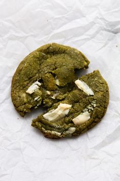 a green cookie with white chocolate chips on it and one piece missing from the cookie