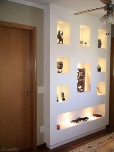 a white wall with several shelves filled with decorative items and lights on each shelf, along with a ceiling fan